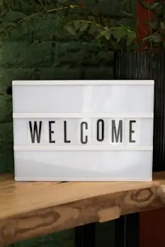 Lightbox with 'Welcome' text on a wooden table against a green wall.