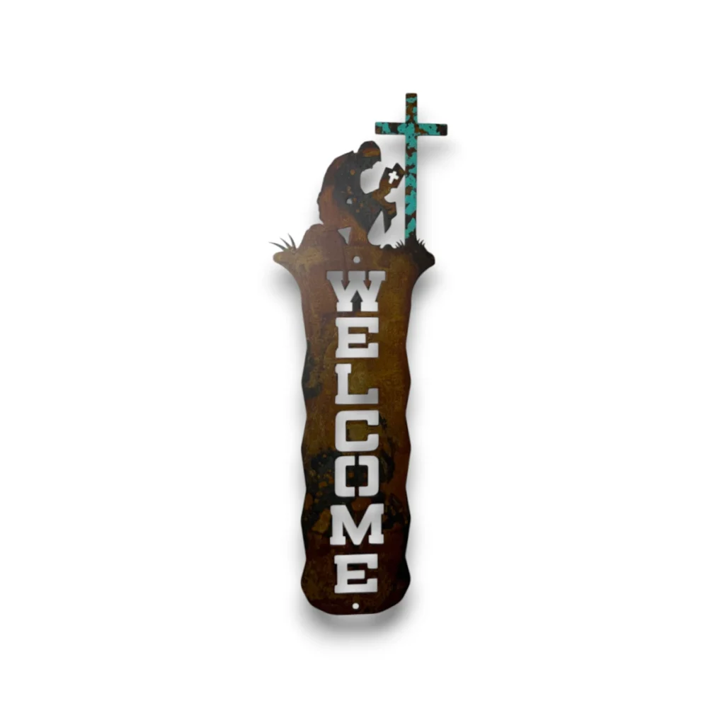 Hand-painted vertical metal welcome sign with praying cowboy, cross, rustic weathered finish, and western faith-inspired decor.